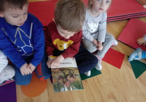 Dzieci oglądają ilustrację z dinozaurami